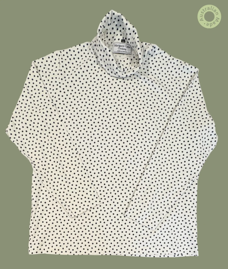 #609 – This top features a white base with a small navy polka dot pattern throughout th